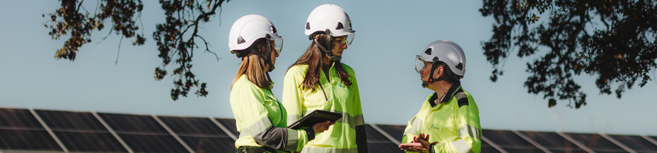 3 workers talking in front of solar panels