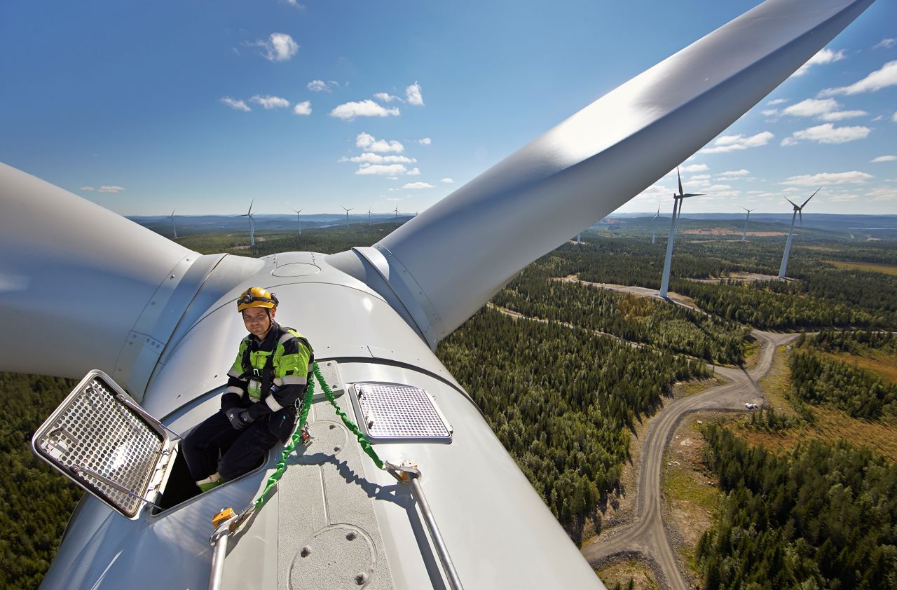 Engineer sitting on top of wind turbine on sunny day