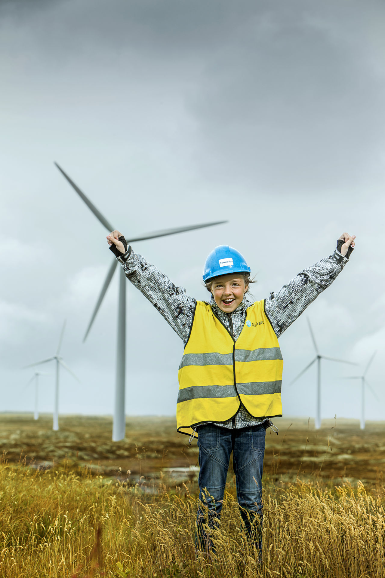 Girl cheering at wind farm with PPE on