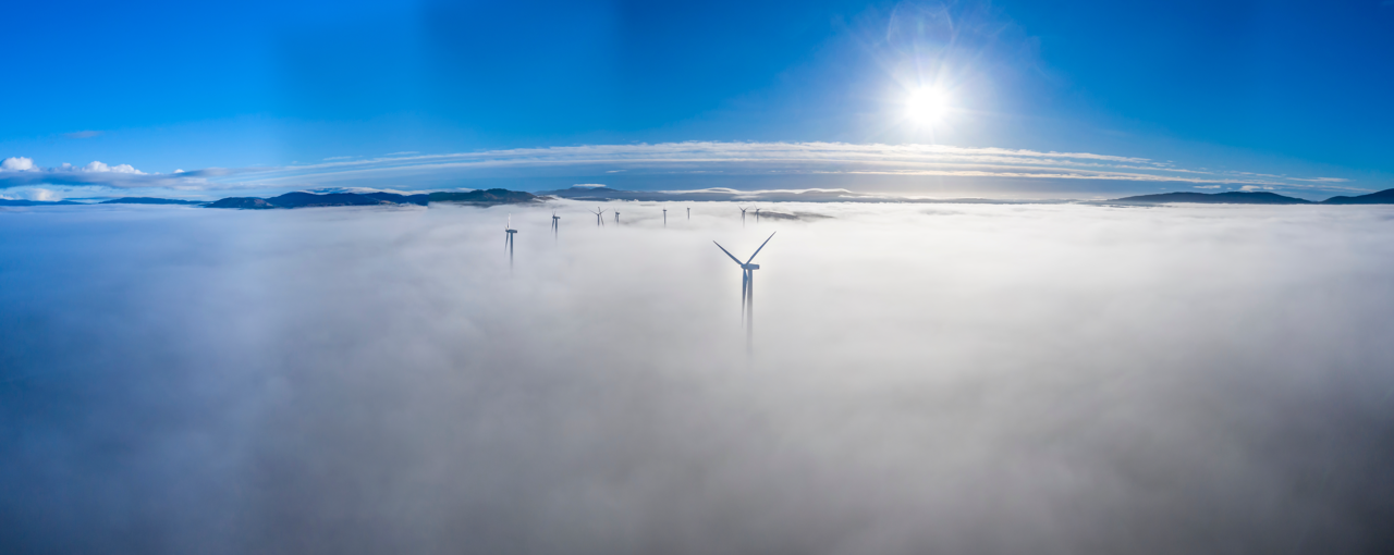 Tips of wind turbines appearing through clouds