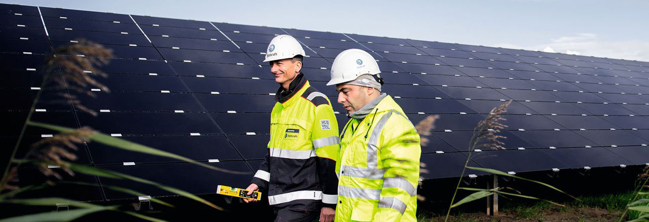 2 engineers walking in front of solar panels