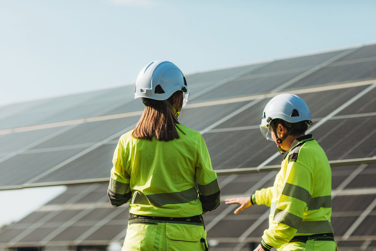 2 engineers walking in front of solar panels